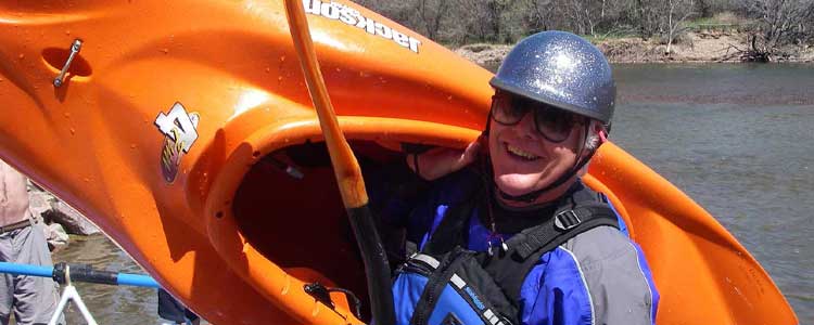 Whitewater kayaker carrying his boat on his shoulder. 